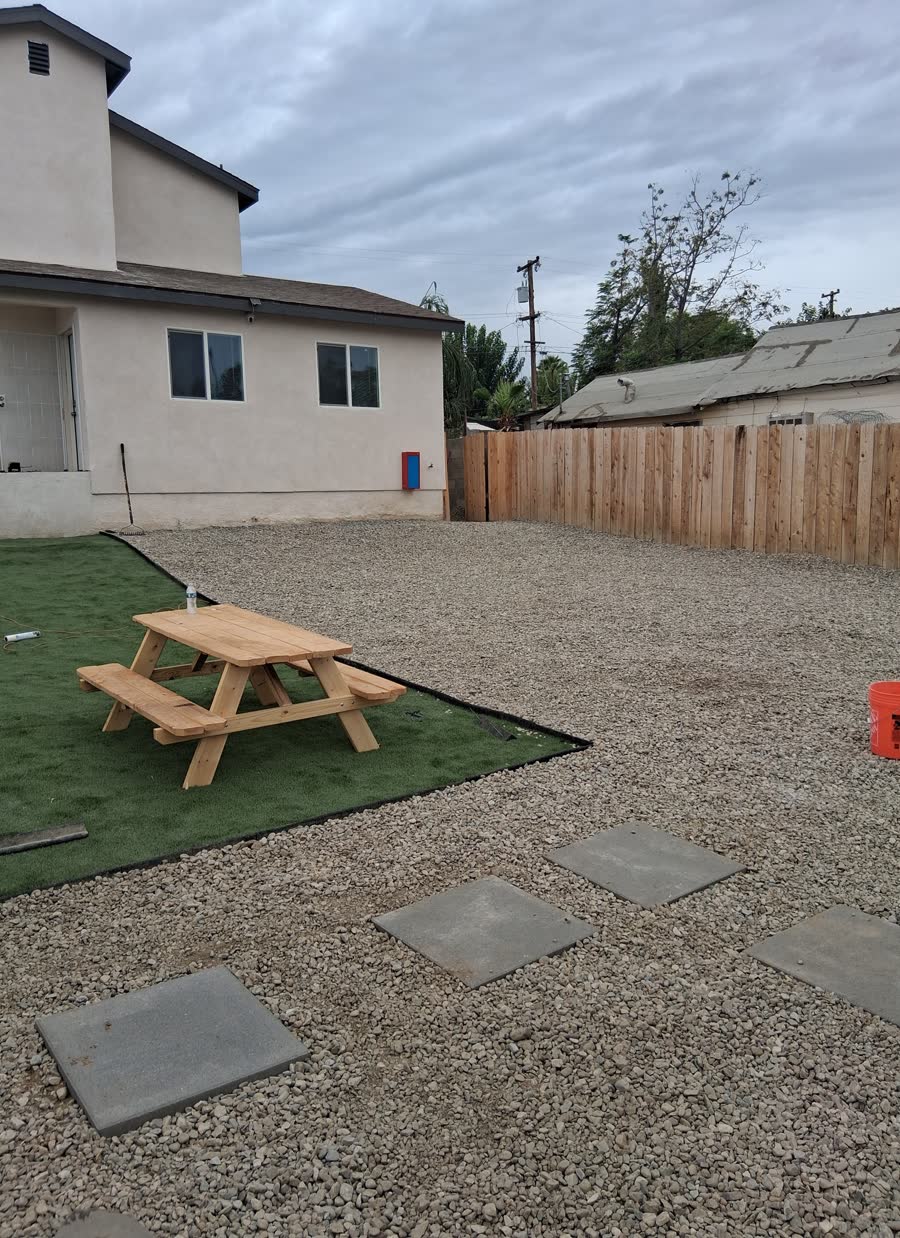 A wooden picnic table on the patch of lawn beside the back door of the house